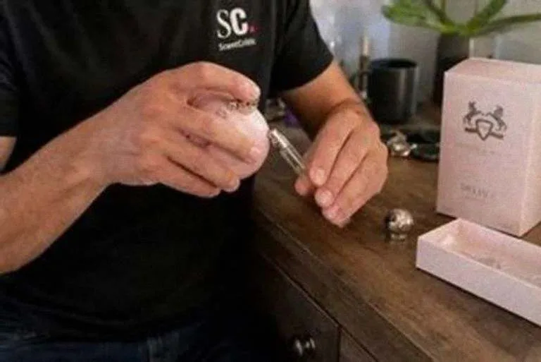 Rellenando un atomizador de viaje de 5 ml desde el frasco de Delina sobre una cómoda
